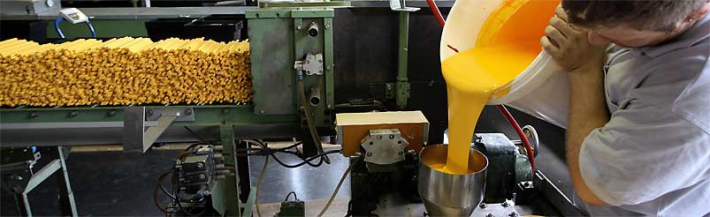 En arbetare häller en gul trögflytande vätska in i en maskin