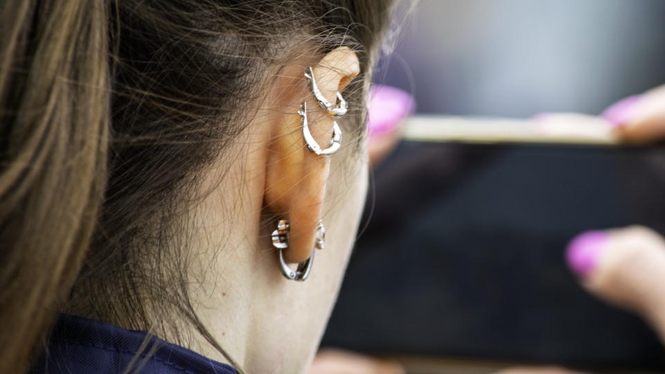 Kvinna med örhängen i metall och smartphone i handen