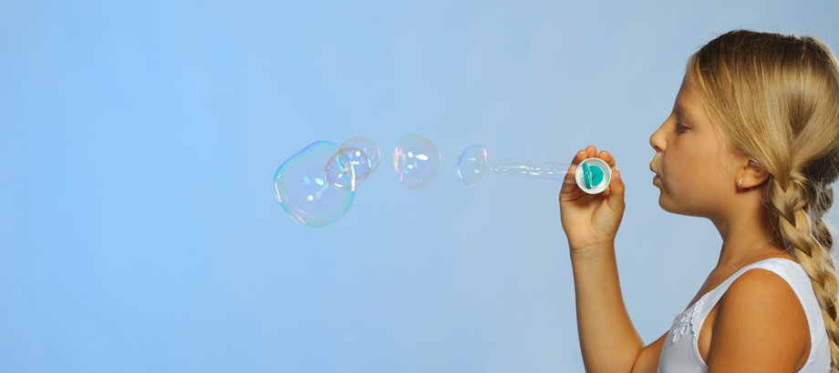 The pretty girl with soap bubbles. A  blue background
