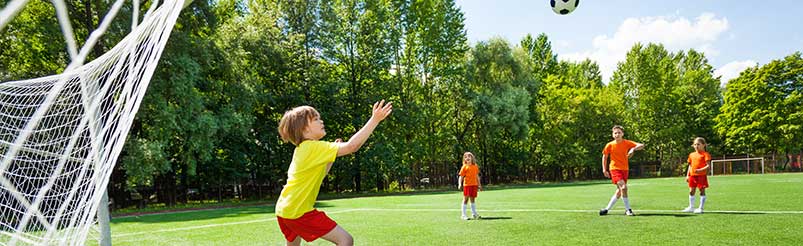 Barn som spelar fotboll på en gräsplan.