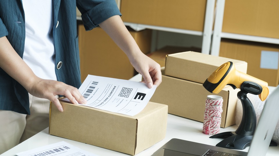 En person klistrar en adresslapp på ett paket.