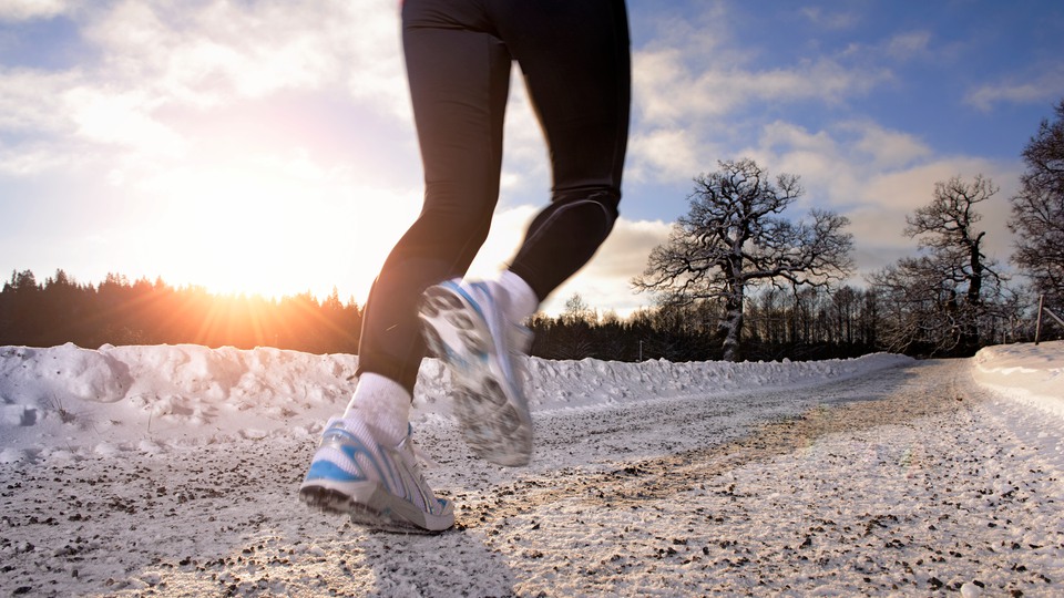 Foto av en löpare med sportskor och funktionskläder på en snöig väg