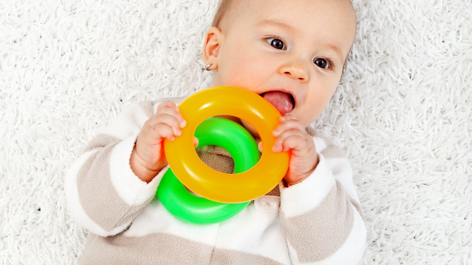 Ett litet barn som stoppar en leksak i munnen.