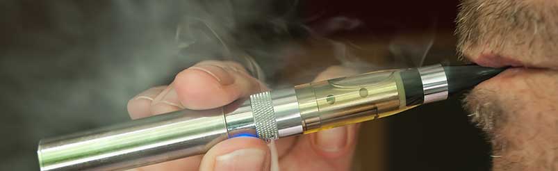 A close-up photo of a person smoking an e-cigarette