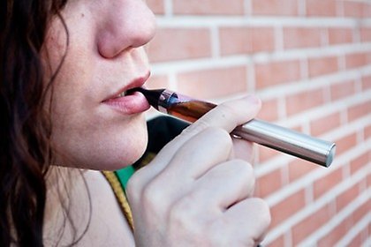 En person som håller en e-cigarett vid munnen.