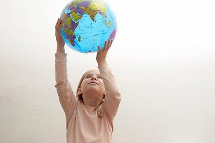En flicka håller upp en badboll som ser ut som en jordglob.